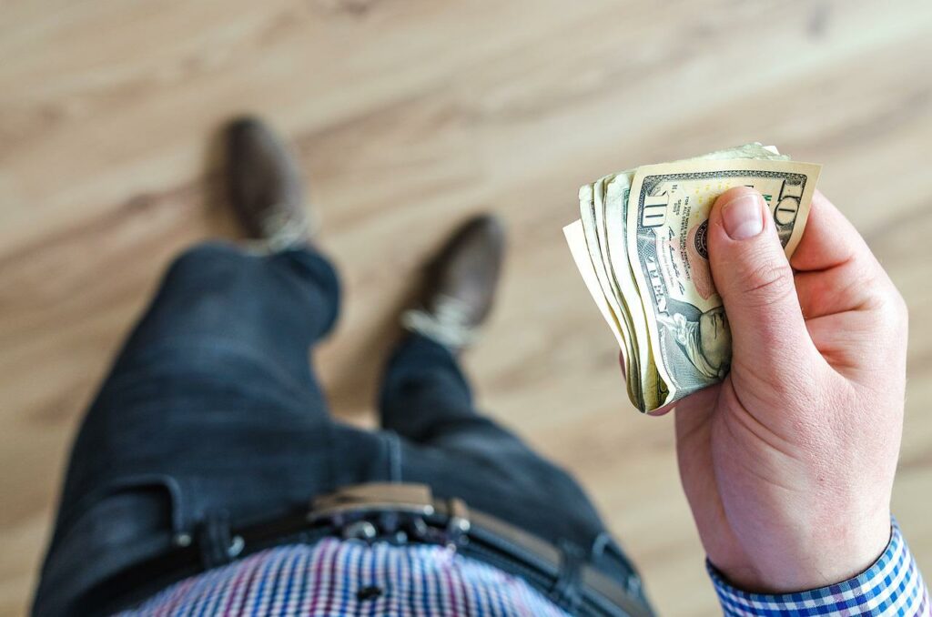 Mann hält Geldschein in den Händen Kredite - nach wie vor auf relativen günstigem Kostenniveau