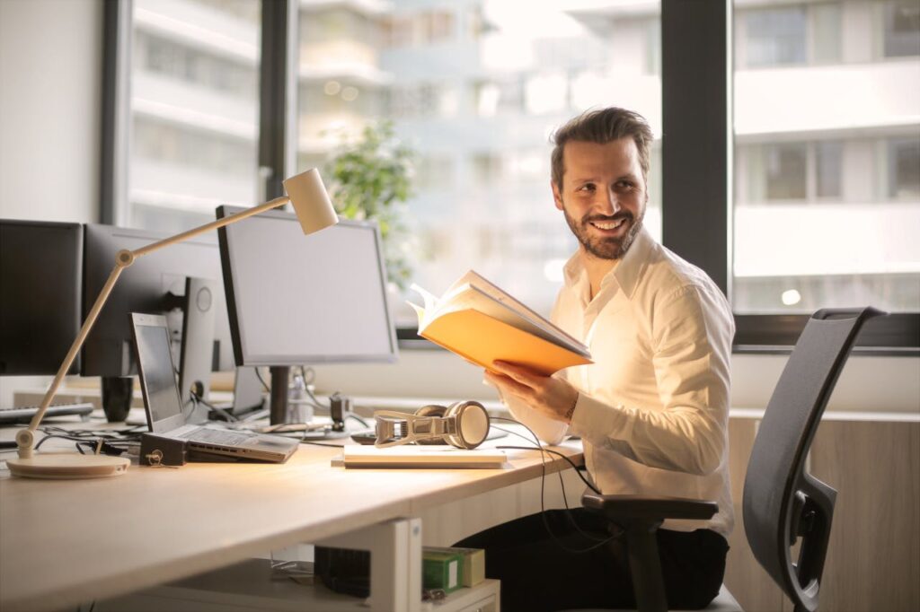 Mann lacht im Büro Alltag im Büro – So macht er mehr Spaß